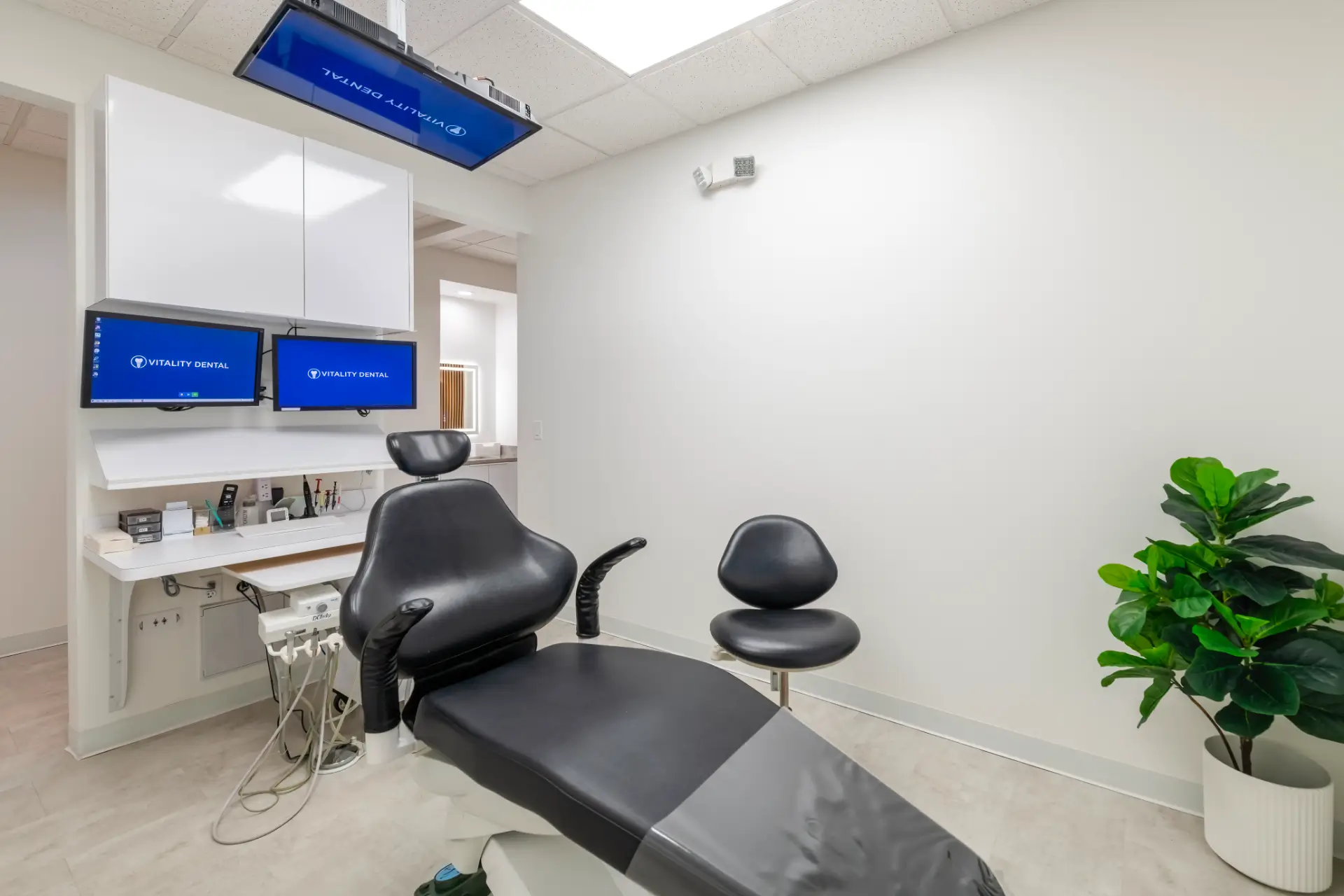 Treatment room at Vitality Dental in Plano with a dental chair and wall monitors